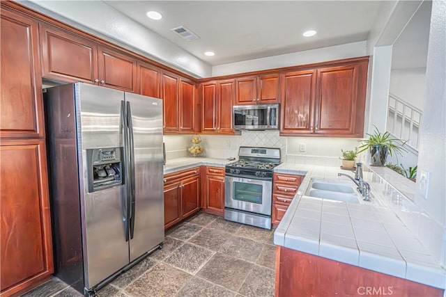 kitchen with visible vents, decorative backsplash, tile counters, a sink, and appliances with stainless steel finishes