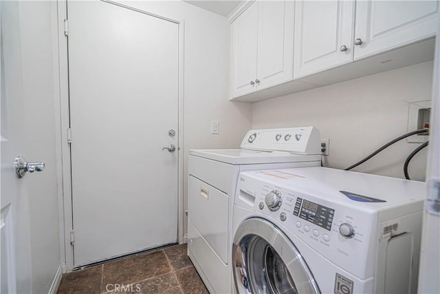 washroom with washing machine and dryer, stone finish flooring, and cabinet space