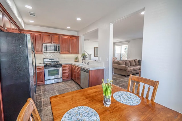 kitchen featuring appliances with stainless steel finishes, a sink, light countertops, backsplash, and visible vents
