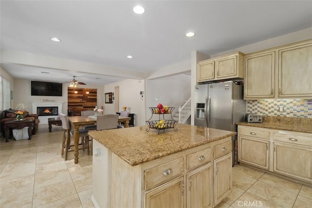 34787 Grotto Hills Dr, Winchester, CA 92596 - kitchen featuring a lit fireplace, a ceiling fan, light brown cabinetry, light stone countertops, and light tile patterned floors