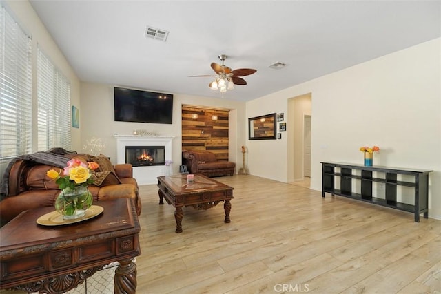 34787 Grotto Hills Dr, Winchester, CA 92596 - living area featuring a glass covered fireplace, a ceiling fan, wood finished floors, and visible vents