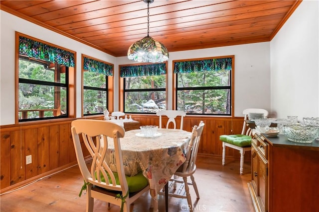 dining area featuring crown molding, wooden walls, and a wainscoted wall