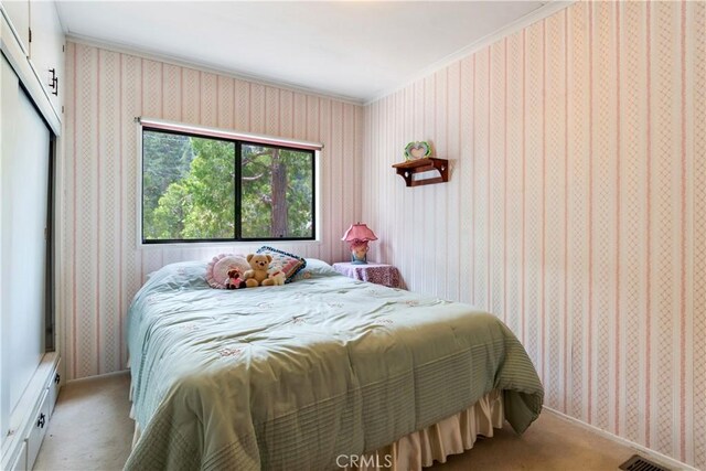 bedroom featuring crown molding, wallpapered walls, and light carpet