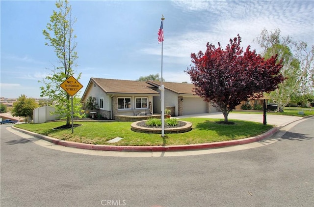 view of front facade with a garage, fence, curved driveway, a front lawn, and stucco siding