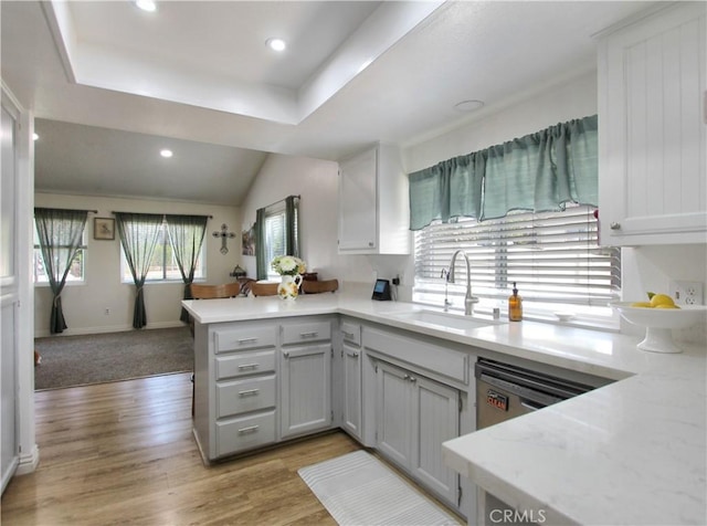 kitchen featuring a peninsula, baseboards, light wood-type flooring, recessed lighting, and a sink