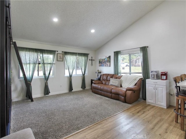 living room with light wood-style floors, a textured ceiling, high vaulted ceiling, recessed lighting, and baseboards