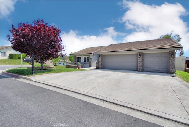 ranch-style home featuring driveway, a tile roof, a front yard, an attached garage, and stone siding