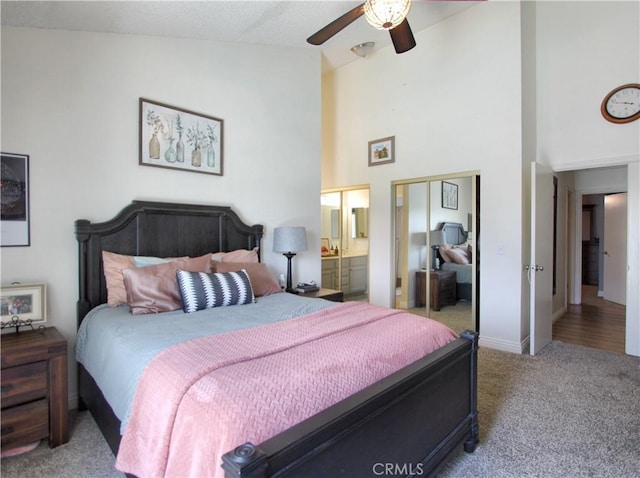 bedroom with carpet floors, high vaulted ceiling, baseboards, ensuite bathroom, and a closet
