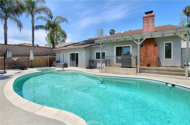 view of swimming pool with fence, a fenced in pool, an in ground hot tub, a patio area, and a grill