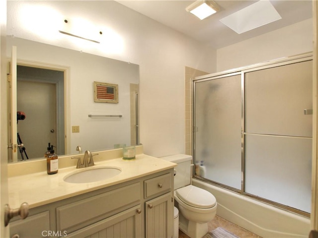 full bathroom with toilet, a skylight, bath / shower combo with glass door, and vanity