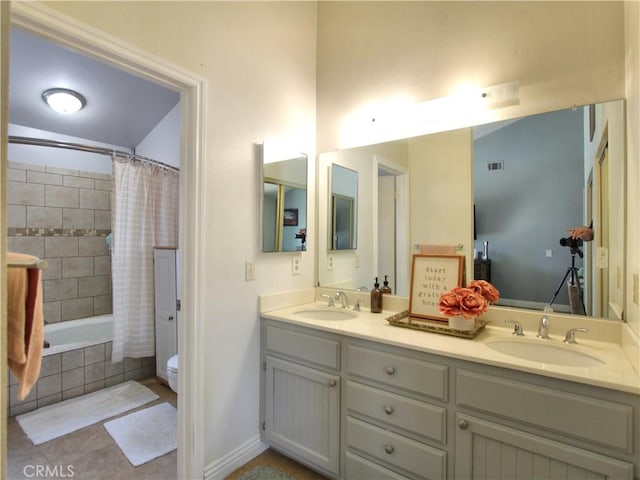 full bathroom featuring a sink, toilet, tiled shower / bath combo, and double vanity