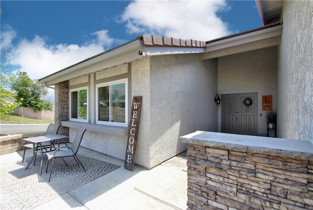 view of exterior entry featuring stucco siding and a patio area