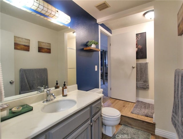 bathroom featuring vanity, toilet, wood finished floors, and visible vents