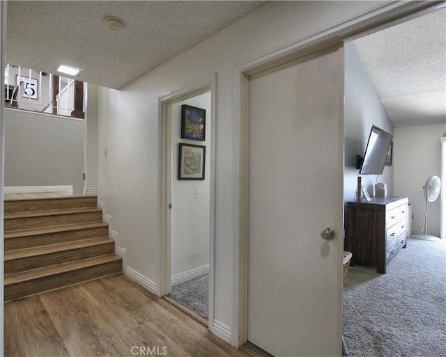 staircase with baseboards, a textured ceiling, and wood finished floors
