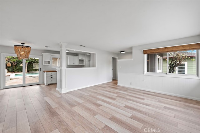 309 W Avenida Valencia, San Clemente, CA 92672 - unfurnished living room featuring an inviting chandelier, light wood-style flooring, baseboards, and wainscoting