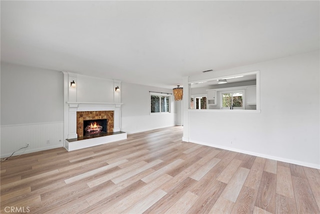 309 W Avenida Valencia, San Clemente, CA 92672 - unfurnished living room featuring light wood-type flooring, a wainscoted wall, a warm lit fireplace, and visible vents