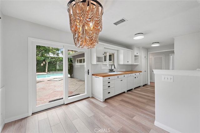 309 W Avenida Valencia, San Clemente, CA 92672 - kitchen with visible vents, a sink, light wood-style floors, wood counters, and white cabinetry