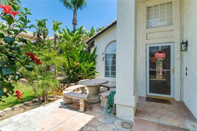 entrance to property featuring a patio and stucco siding