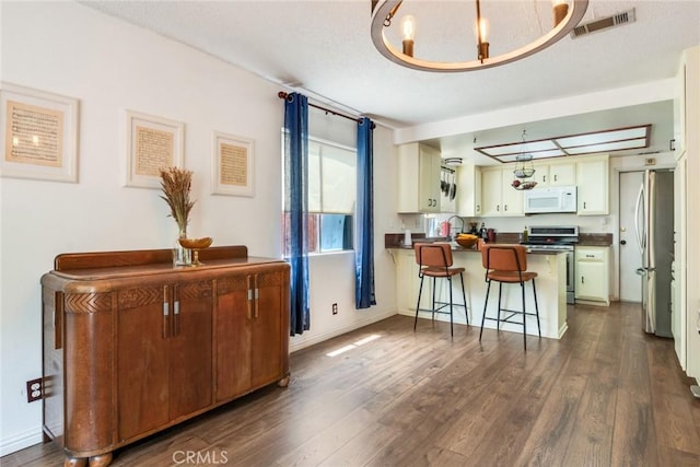 interior space featuring dark countertops, appliances with stainless steel finishes, a peninsula, and dark wood-type flooring