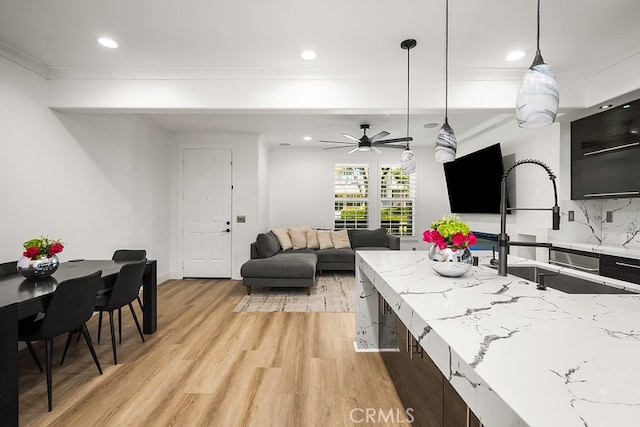 kitchen featuring a sink, light wood finished floors, a ceiling fan, decorative light fixtures, and recessed lighting