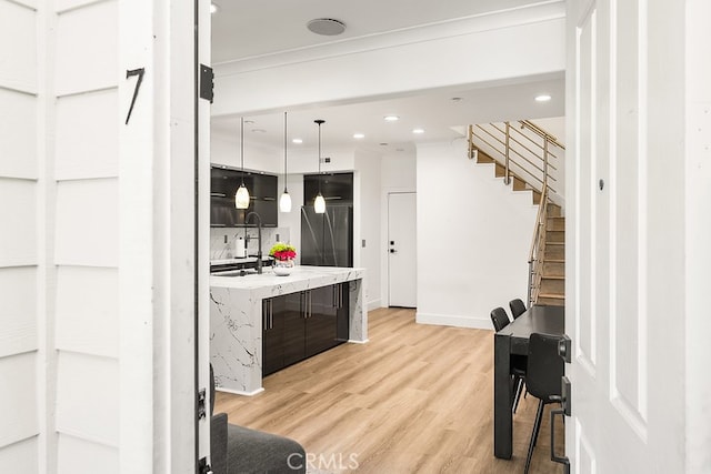 kitchen with pendant lighting, a sink, baseboards, light wood finished floors, and recessed lighting