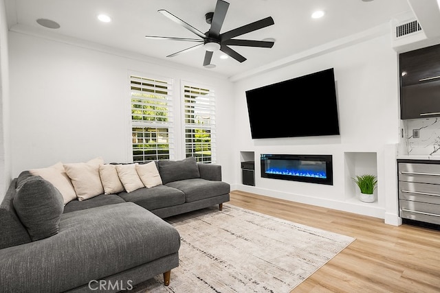living room with ceiling fan, light wood-style floors, recessed lighting, visible vents, and ornamental molding