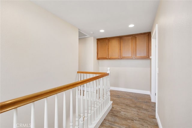 hallway featuring recessed lighting, light wood-style flooring, baseboards, and an upstairs landing