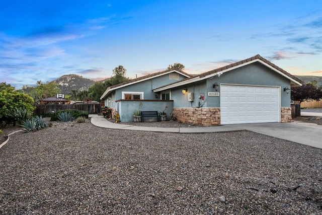 16016 Spangler Peak Rd, Ramona, CA 92065 - view of front of home featuring fence, an attached garage, stucco siding, and stone siding