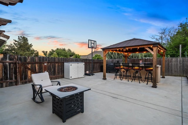 16016 Spangler Peak Rd, Ramona, CA 92065 - patio terrace at dusk with a fenced backyard, outdoor dry bar, a gazebo, and a fire pit