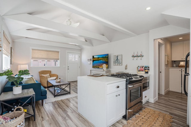 3534 Ocean Dr, Oxnard, CA 93035 - kitchen with light countertops, stainless steel gas range, white cabinets, light wood finished floors, and vaulted ceiling with beams