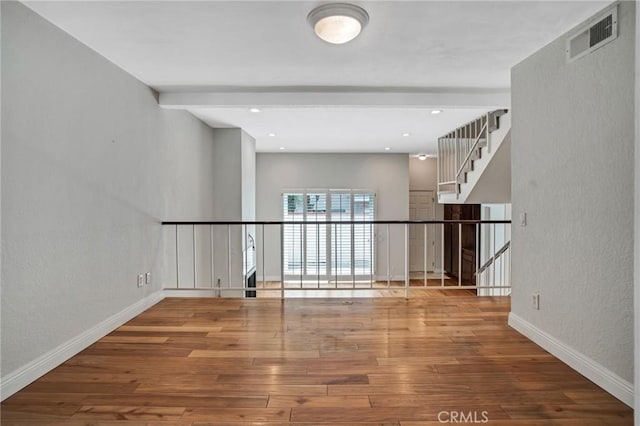 unfurnished room featuring visible vents, a textured wall, hardwood / wood-style floors, baseboards, and recessed lighting