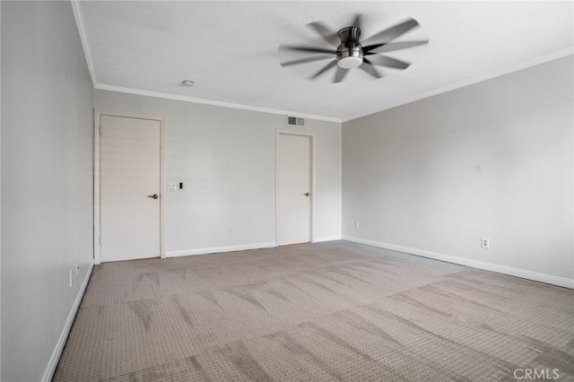 empty room with a ceiling fan, visible vents, carpet floors, baseboards, and ornamental molding