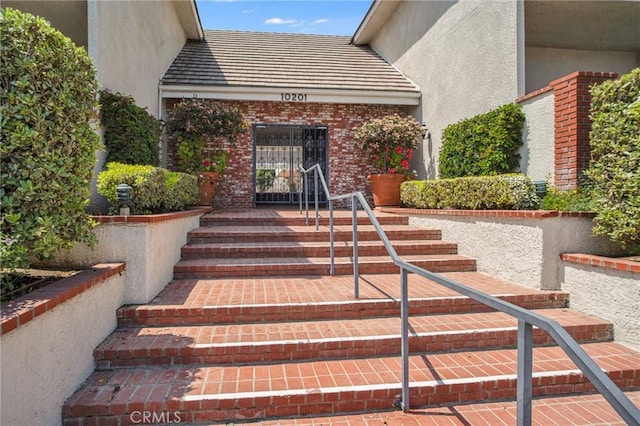 property entrance with brick siding and stucco siding