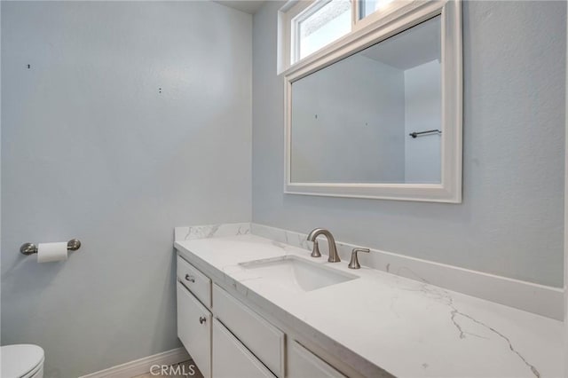 half bathroom featuring vanity and toilet