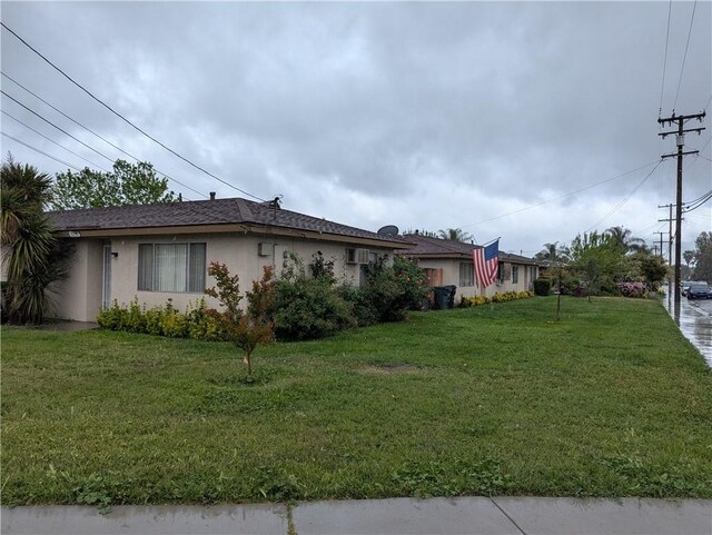 view of side of home featuring stucco siding and a yard