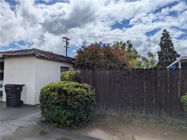 view of side of home featuring stucco siding and fence