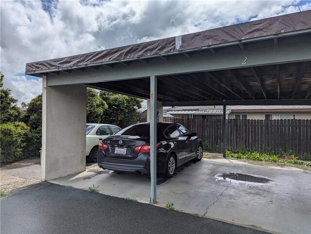 covered parking lot featuring fence