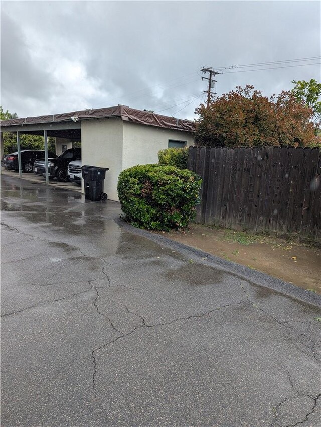 view of side of home featuring covered parking and fence