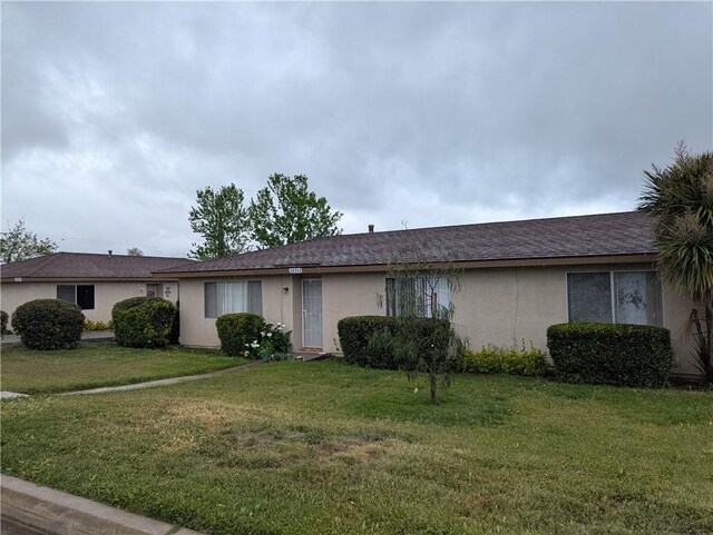 single story home featuring stucco siding and a front lawn