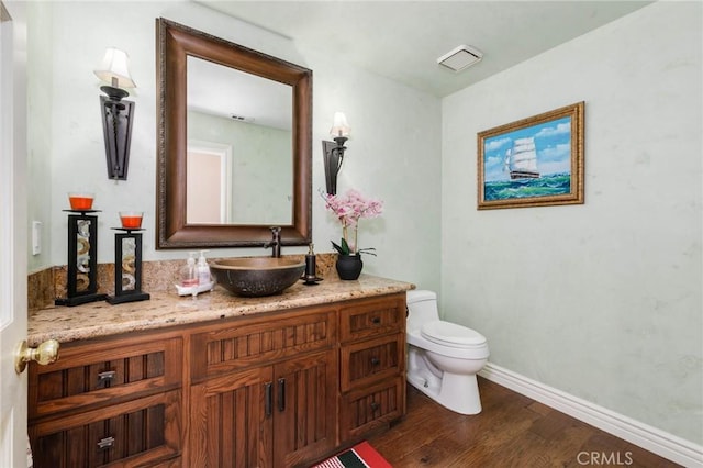 bathroom with toilet, baseboards, wood finished floors, and vanity