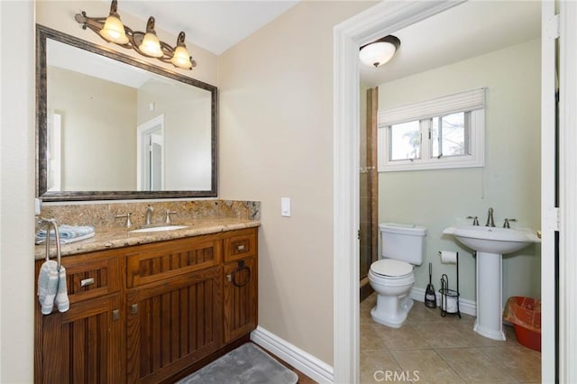 bathroom with baseboards, a sink, tile patterned floors, and toilet