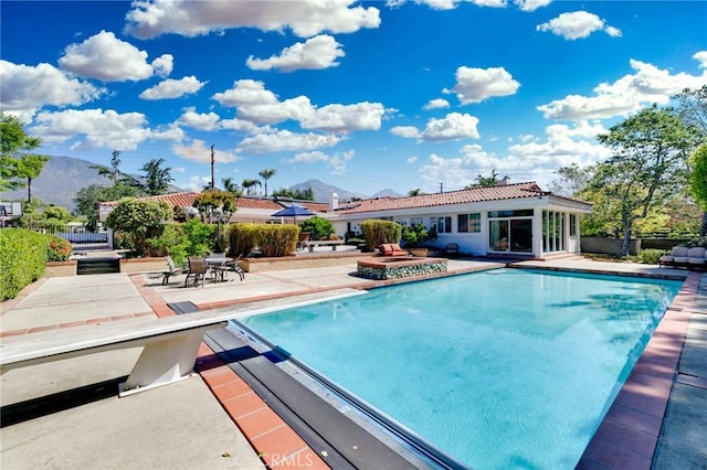 pool featuring a diving board, a mountain view, a jacuzzi, and a patio area