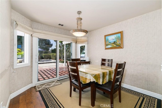 dining area with wallpapered walls, visible vents, baseboards, and hardwood / wood-style floors