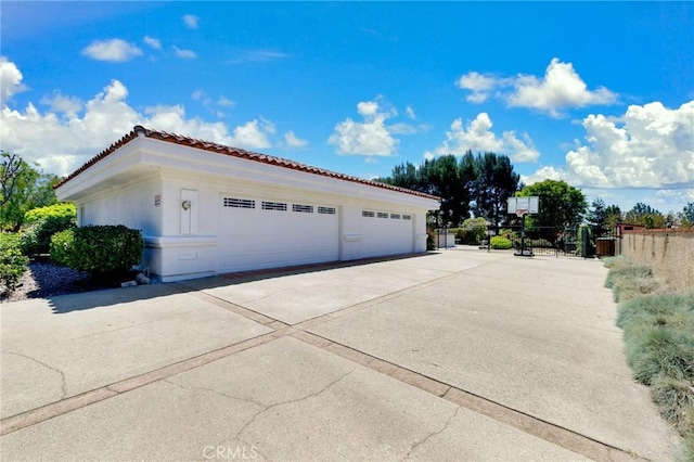 view of side of property with stucco siding, a tiled roof, and a detached garage