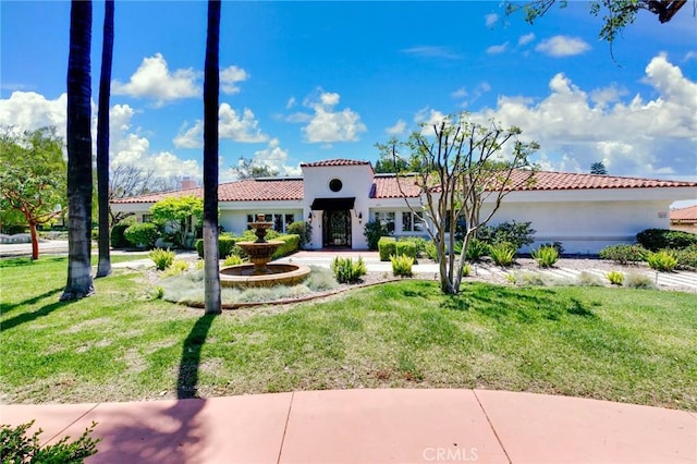 mediterranean / spanish house featuring a tile roof, a front yard, and stucco siding