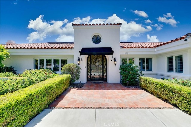 entrance to property with stucco siding and a tile roof