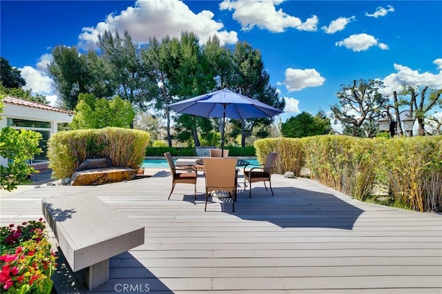 wooden terrace with outdoor dining area and an outdoor pool