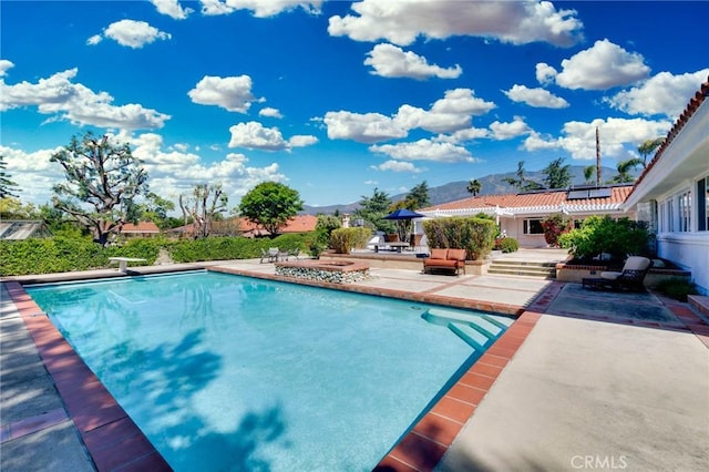 pool featuring a patio, a mountain view, and a diving board