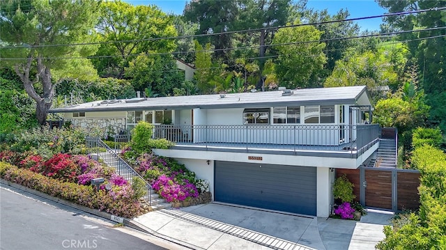 view of front facade featuring stairs, an attached garage, stucco siding, and concrete driveway