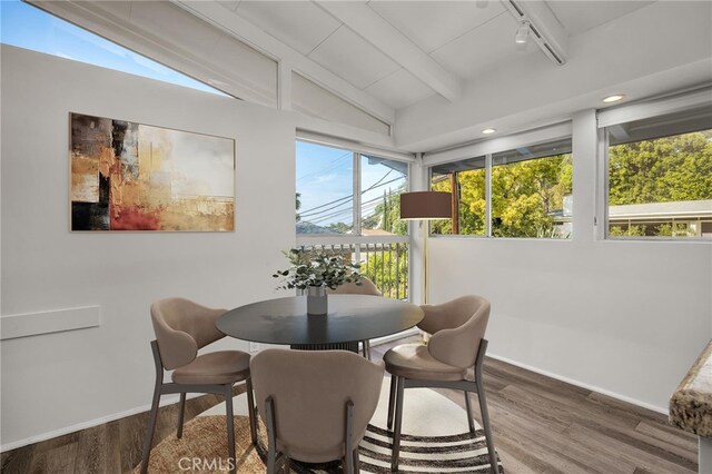 sunroom / solarium featuring beamed ceiling and rail lighting